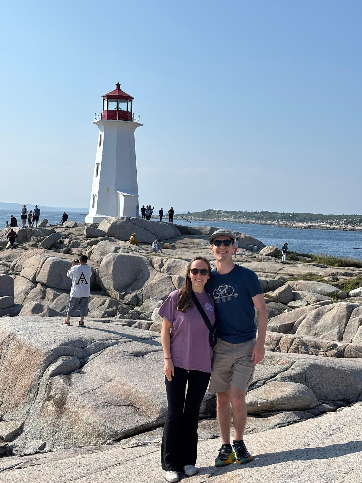 Couple standing on rocks near a lighthouse.