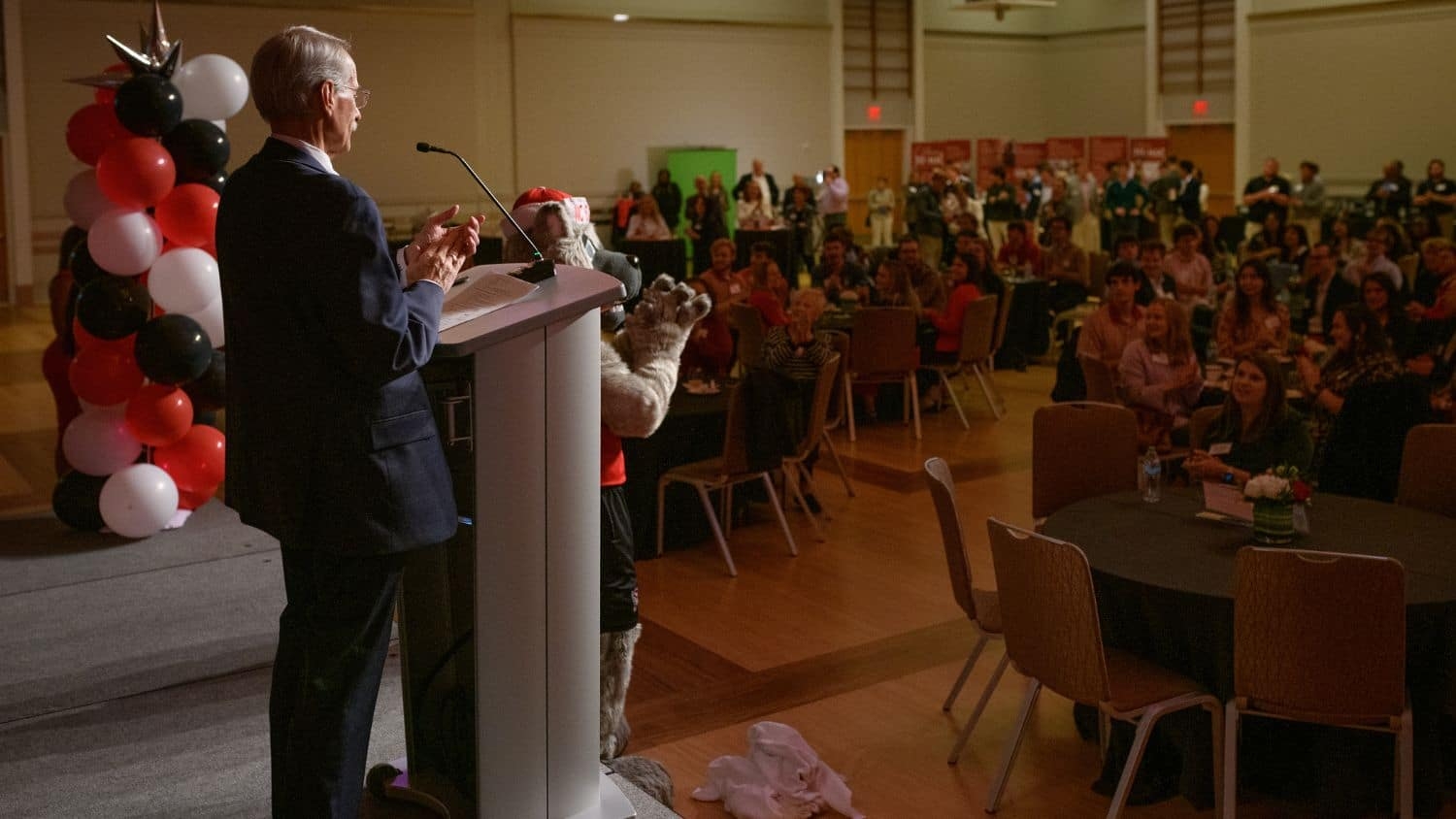 Scott Showalter addressing a large crowd at the MAC celebration, all of whom are applauding